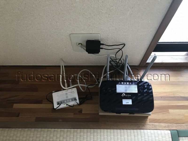 一棟マンションの空室対策として実際に著者が導入した無料インターネット設備の設置写真。無線LANルーターと配線機器が室内に設置されており、入居者向けのインターネット無料化によって入居率向上と空室損失の削減を実現した事例