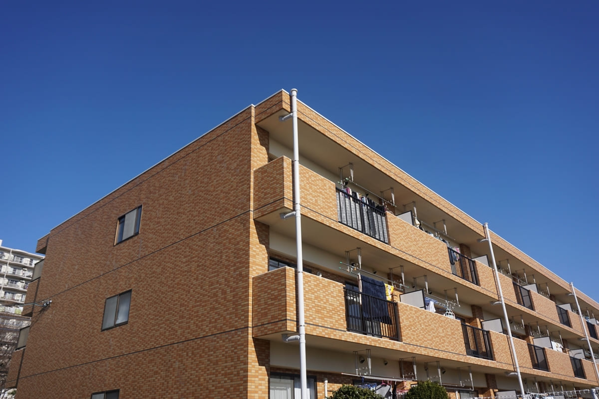 青空の下に建つ3階建ての一棟マンションの外観。これから不動産投資を始めようとする人に向けた、現実的な収益物件のイメージとして掲載。