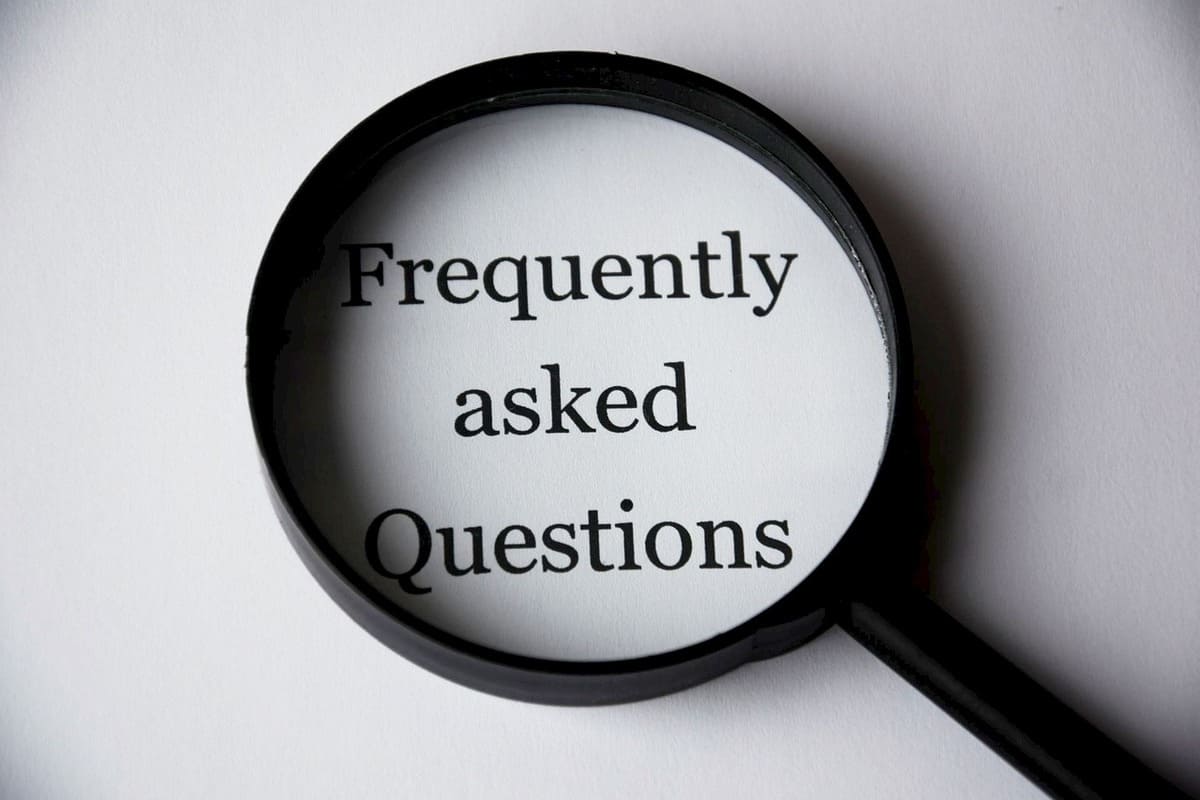 白い背景に置かれた虫眼鏡の中に「Frequently asked Questions（よくある質問）」と書かれた文字が映るイメージ。FAQセクションの開始を示す視覚的なアイキャッチ。